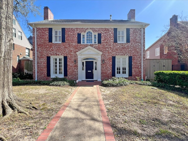 view of front of property featuring brick siding and a chimney