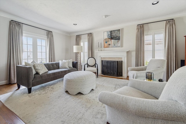 living area featuring a wealth of natural light, wood finished floors, a fireplace, and crown molding