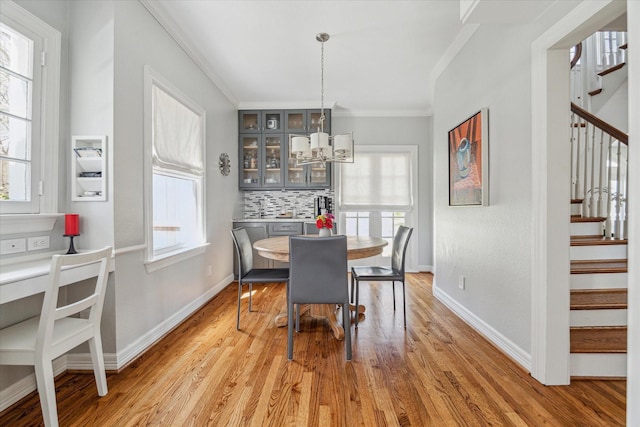 dining area featuring baseboards, stairs, ornamental molding, light wood-style flooring, and an inviting chandelier