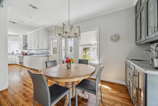 dining area with visible vents, baseboards, crown molding, and light wood-style floors