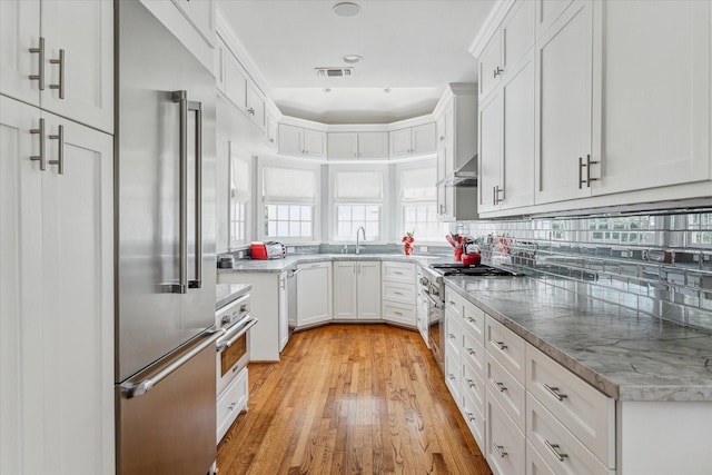 kitchen featuring visible vents, decorative backsplash, light wood-style flooring, appliances with stainless steel finishes, and white cabinetry