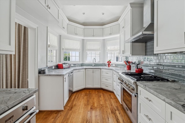 kitchen featuring decorative backsplash, white cabinets, wall chimney exhaust hood, and stainless steel appliances