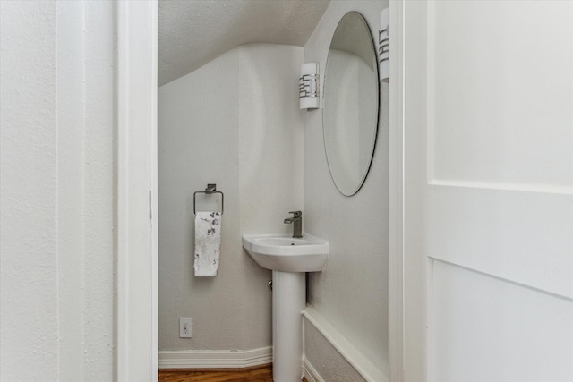 bathroom featuring a sink, wood finished floors, baseboards, and a textured ceiling