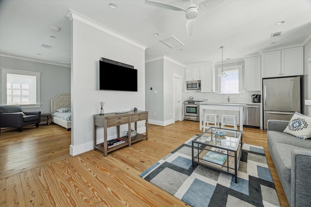 living area featuring visible vents, light wood-style flooring, and crown molding