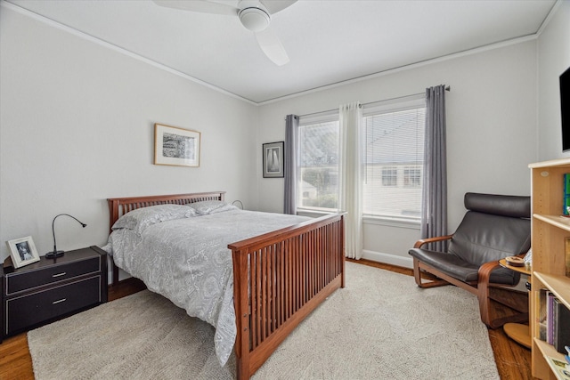 bedroom with crown molding, wood finished floors, baseboards, and ceiling fan