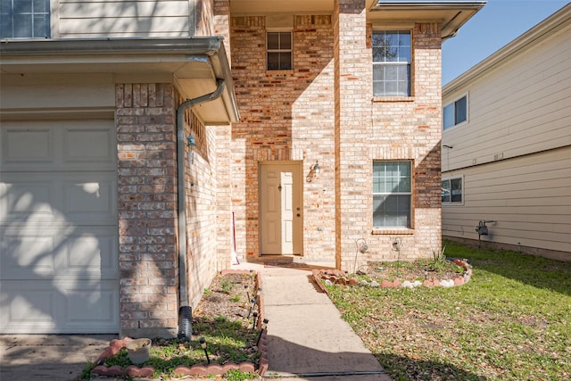 doorway to property featuring a garage and brick siding