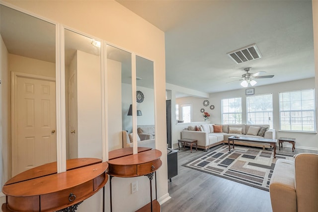 living room with wood finished floors, visible vents, and a ceiling fan