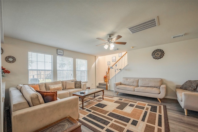 living room with stairway, visible vents, and wood finished floors