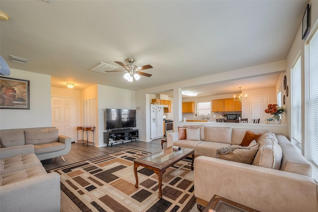 living room featuring visible vents, wood finished floors, and ceiling fan with notable chandelier