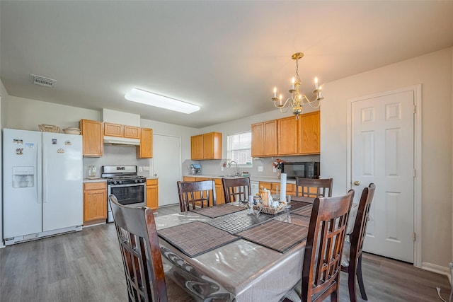 dining area featuring visible vents, a chandelier, and wood finished floors