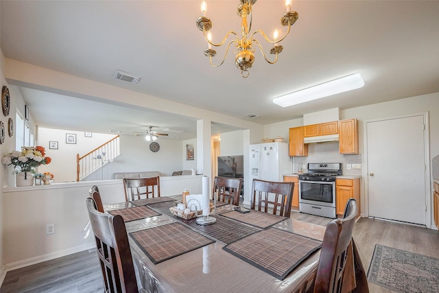 dining area with ceiling fan with notable chandelier, stairway, baseboards, and light wood-style floors