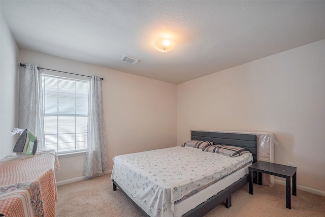 bedroom with baseboards, visible vents, and light colored carpet