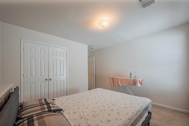 carpeted bedroom featuring a closet, visible vents, and baseboards