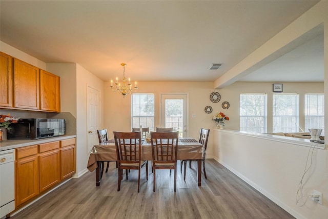 dining area featuring beam ceiling, visible vents, light wood-style floors, a chandelier, and baseboards