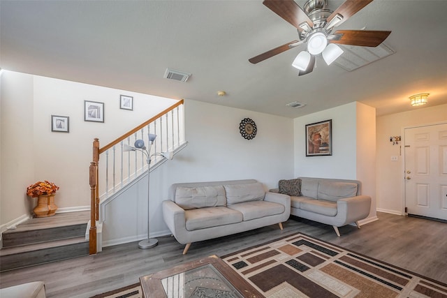 living area with stairway, ceiling fan, visible vents, and wood finished floors