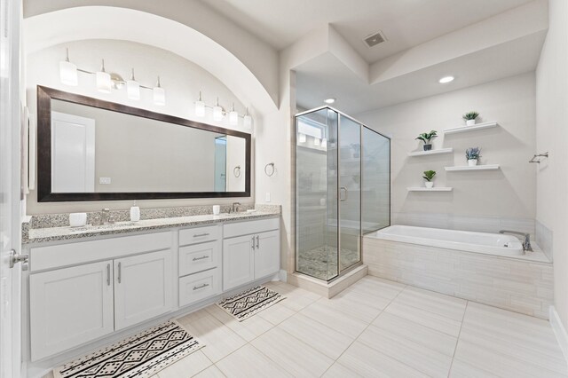 full bath with double vanity, a stall shower, visible vents, a bath, and a sink