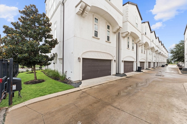 exterior space featuring an attached garage, fence, and concrete driveway