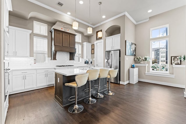 kitchen with a breakfast bar, visible vents, light countertops, stainless steel fridge with ice dispenser, and dark wood-style floors