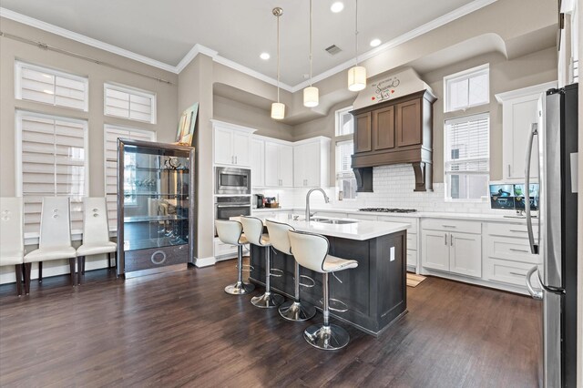 kitchen with dark wood-style floors, stainless steel appliances, light countertops, ornamental molding, and a sink