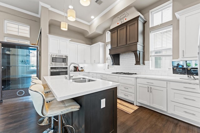 kitchen with dark wood-style flooring, crown molding, stainless steel appliances, light countertops, and a sink