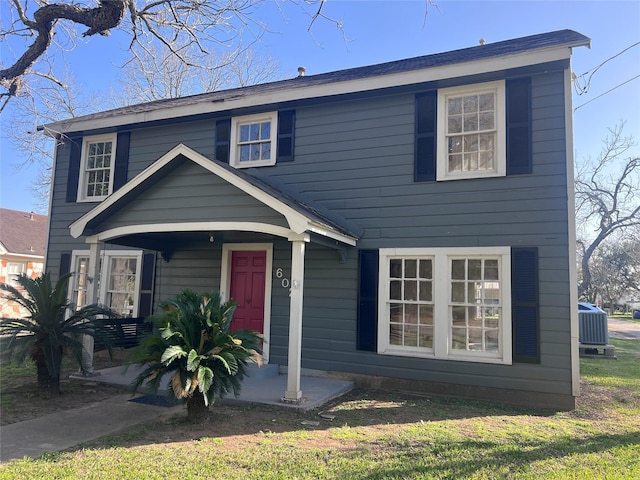 view of front of property with central air condition unit, covered porch, and a front yard