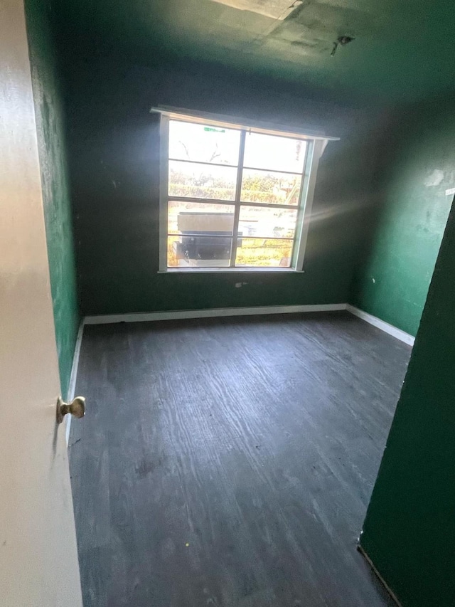 additional living space with baseboards and wood finished floors