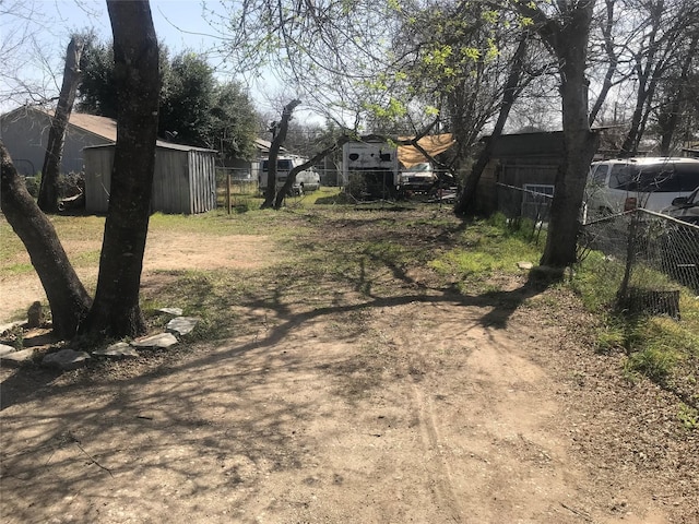 view of yard with a storage shed, an outdoor structure, and fence