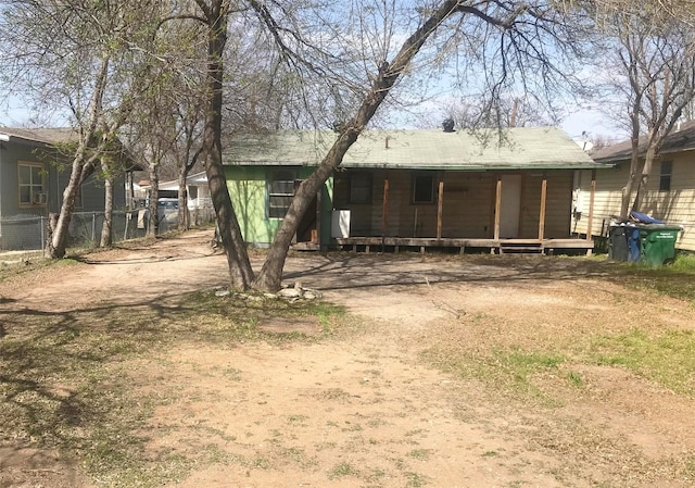 rear view of property featuring driveway and fence