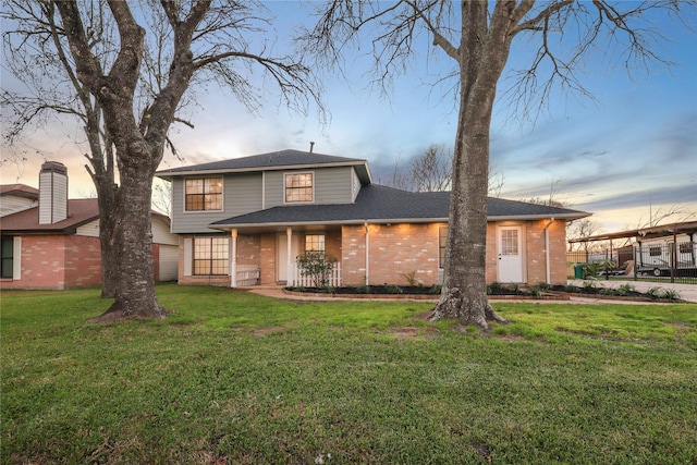 traditional home featuring a front yard, brick siding, and roof with shingles