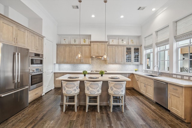 kitchen with a center island, a breakfast bar area, light countertops, appliances with stainless steel finishes, and a sink