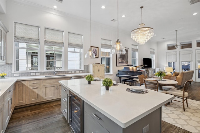 kitchen featuring light countertops, dark wood-type flooring, ornamental molding, a sink, and beverage cooler