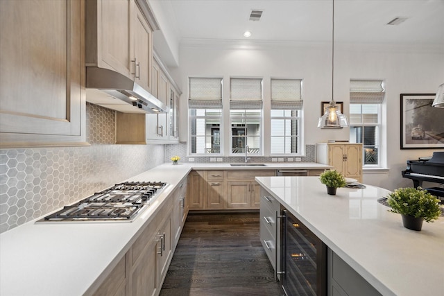 kitchen featuring beverage cooler, stainless steel gas stovetop, ornamental molding, and light countertops