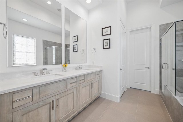 full bath featuring double vanity, a shower stall, a sink, and tile patterned floors