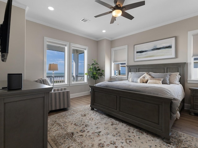 bedroom with light wood finished floors, visible vents, and crown molding