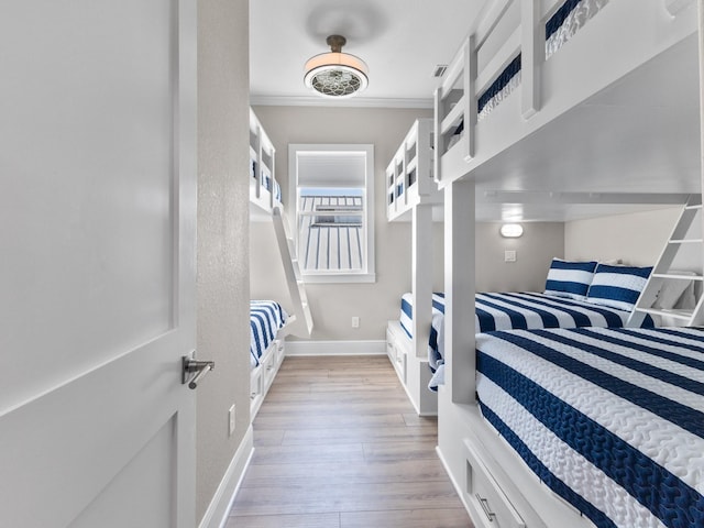 bedroom with ornamental molding, light wood-type flooring, and baseboards