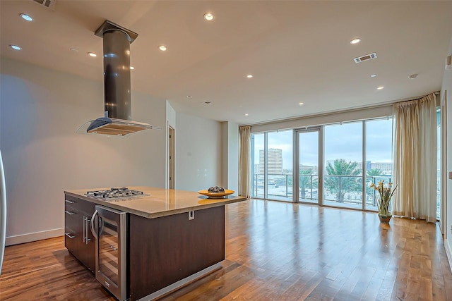 kitchen with beverage cooler, wood finished floors, visible vents, open floor plan, and a center island