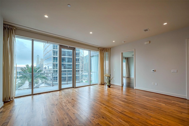 empty room featuring hardwood / wood-style flooring, plenty of natural light, baseboards, and recessed lighting