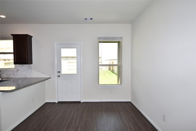 unfurnished dining area with visible vents, dark wood finished floors, and baseboards