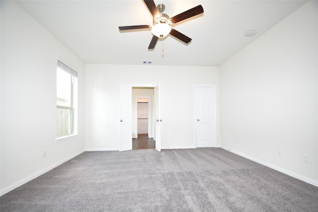 unfurnished room with carpet floors, baseboards, visible vents, and ceiling fan