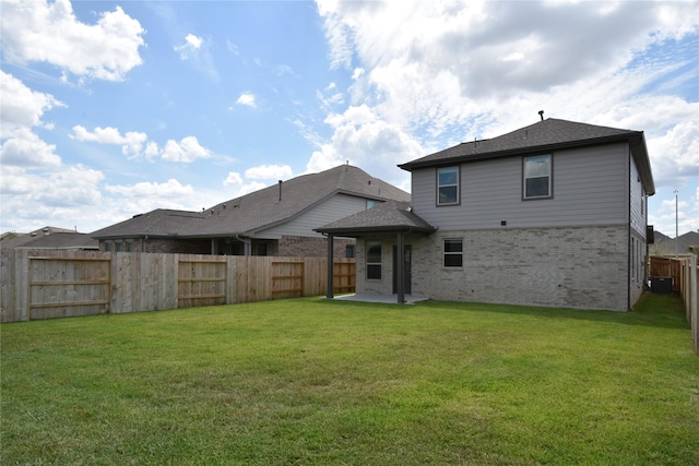 back of house with brick siding, a yard, a fenced backyard, and a patio