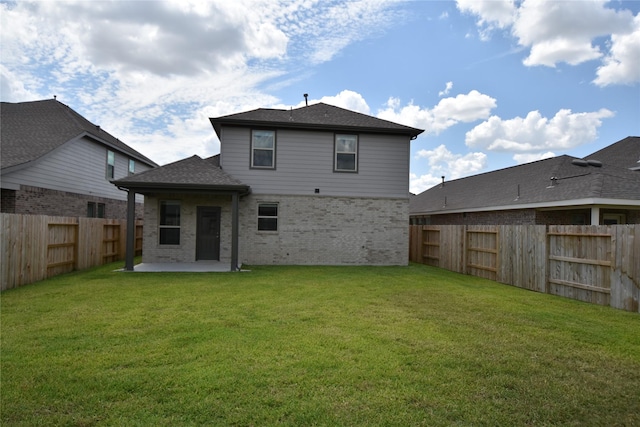 back of property featuring a fenced backyard, brick siding, roof with shingles, a lawn, and a patio area