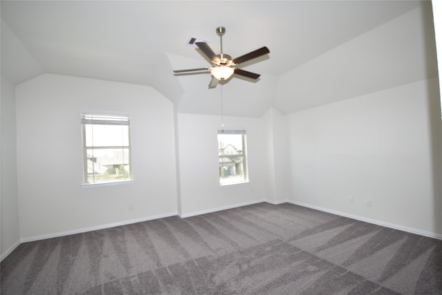 unfurnished room featuring lofted ceiling, plenty of natural light, and dark colored carpet