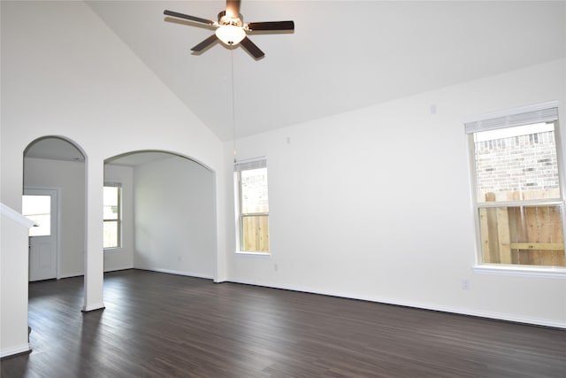 unfurnished room with arched walkways, dark wood-style flooring, a ceiling fan, high vaulted ceiling, and baseboards