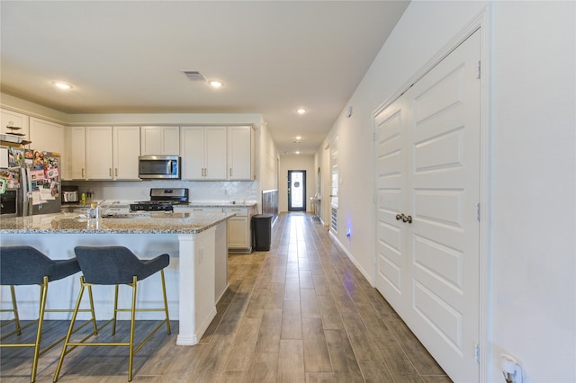 5723 Morning Vista Rd, Katy, TX 77493 - kitchen featuring light stone counters, stainless steel appliances, visible vents, backsplash, and light wood-type flooring