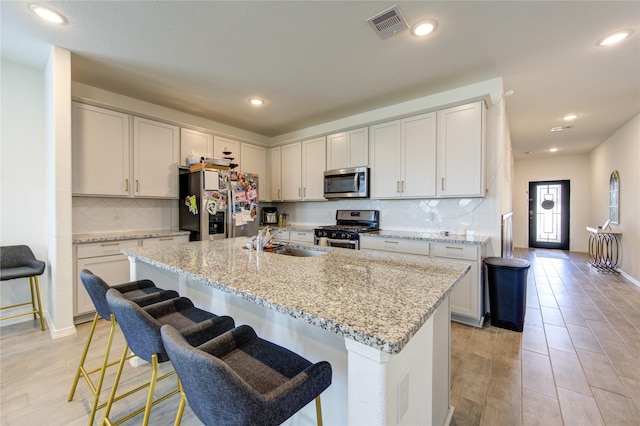5723 Morning Vista Rd, Katy, TX 77493 - kitchen featuring visible vents, light stone counters, appliances with stainless steel finishes, a kitchen breakfast bar, and a sink