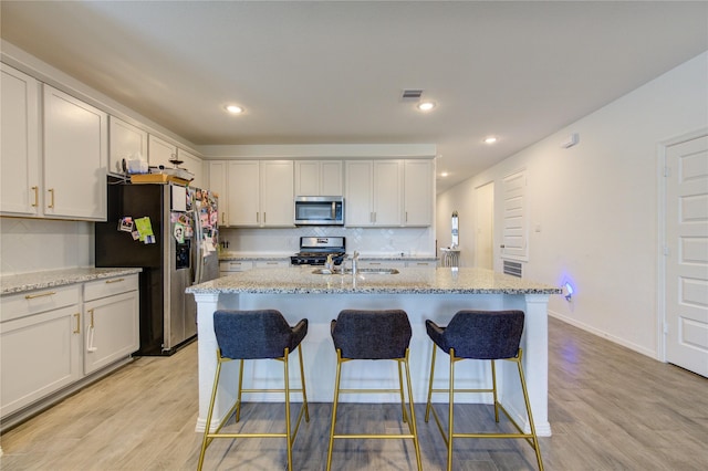 5723 Morning Vista Rd, Katy, TX 77493 - kitchen featuring light wood-style floors, visible vents, a kitchen bar, and appliances with stainless steel finishes