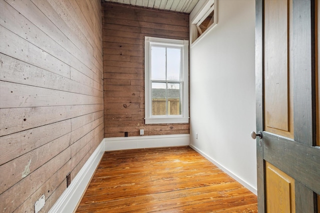 empty room with wooden walls and light wood finished floors