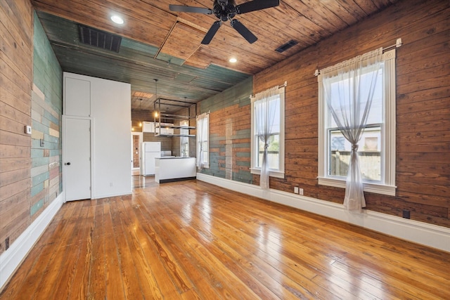 unfurnished room featuring wooden ceiling, wooden walls, visible vents, and hardwood / wood-style flooring