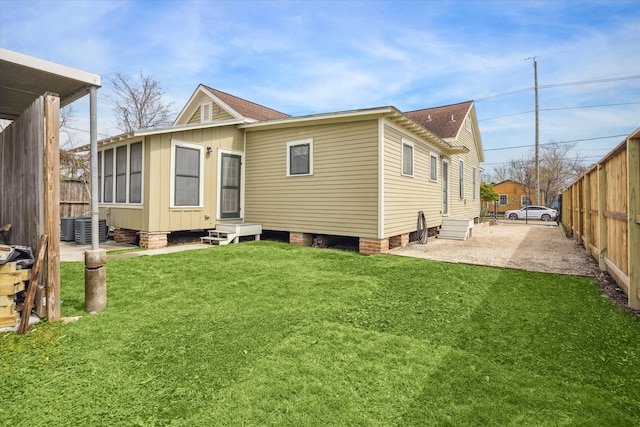 back of property featuring entry steps, central air condition unit, fence, and a lawn