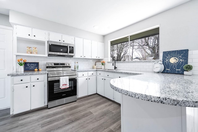 kitchen featuring light wood-style flooring, a sink, white cabinets, appliances with stainless steel finishes, and decorative backsplash